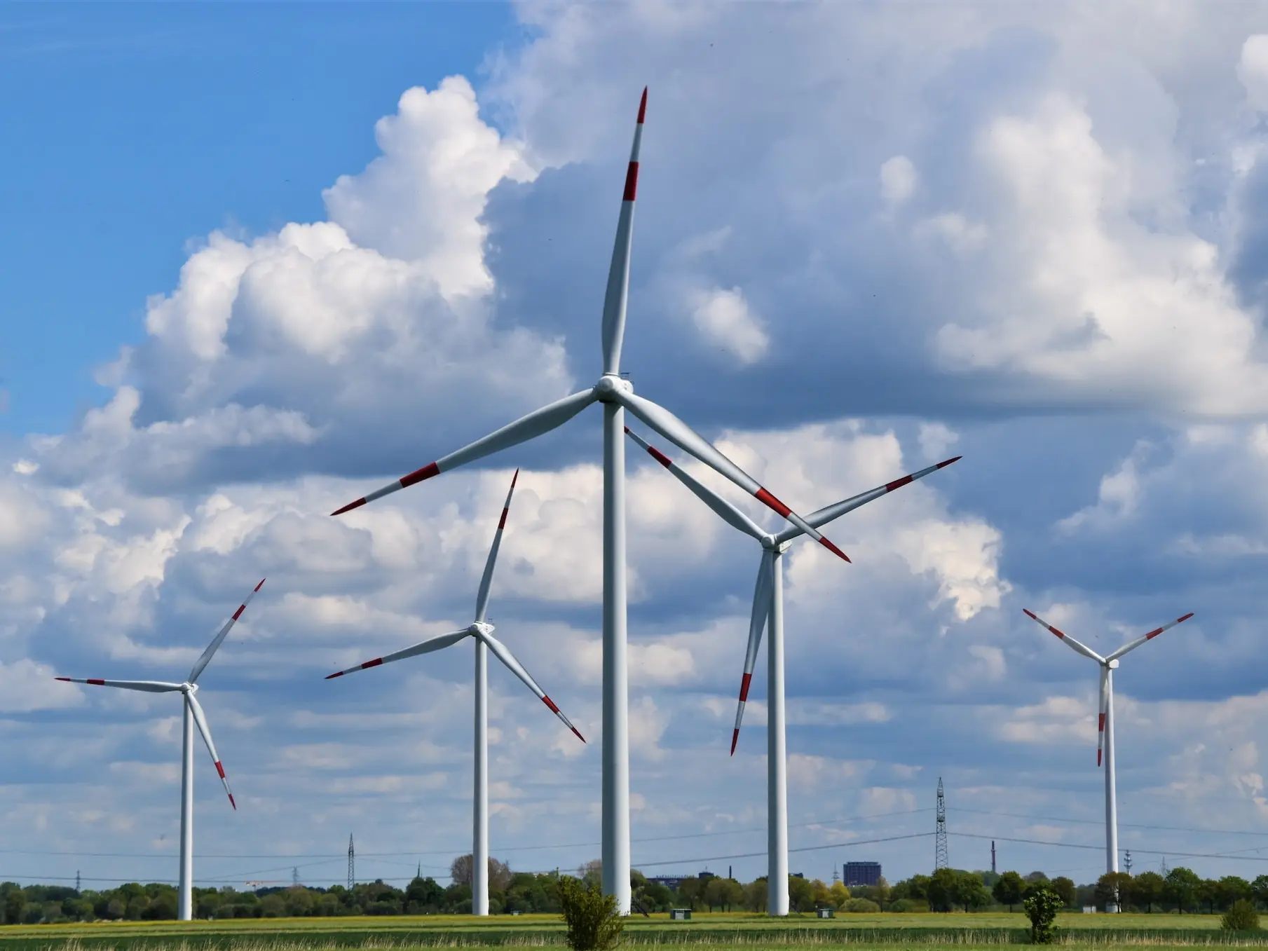 white wind turbines on green grass field under blue and white cloudy sky during daytime